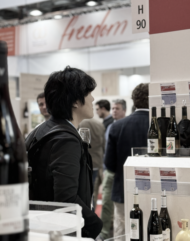 A wine fair stand with bottles on display, a visitor browsing the shelves